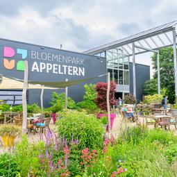 Entree van Bloemenpark Appeltern met bloemenborders en het parklogo op de achtergrond.
