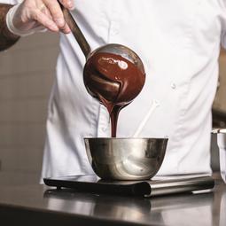 Kok lepelt chocolade uit een kom