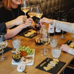 Mensen proosten aan tafel met een kaasplankje
