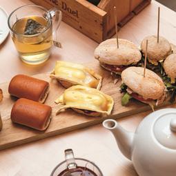 Tafel met belegde broodjes, thee en zoete gebakjes