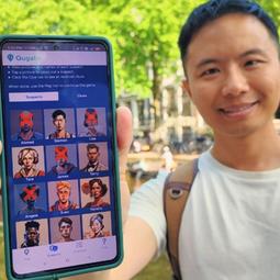 Man toont smartphone met verdachtenlijst tijdens een outdoor citygame.
