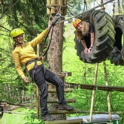 Persoon balanceert op touwen hoog tussen de bomen